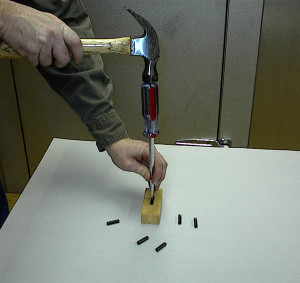 Insert screwdriver into pin by tapping with hammer.